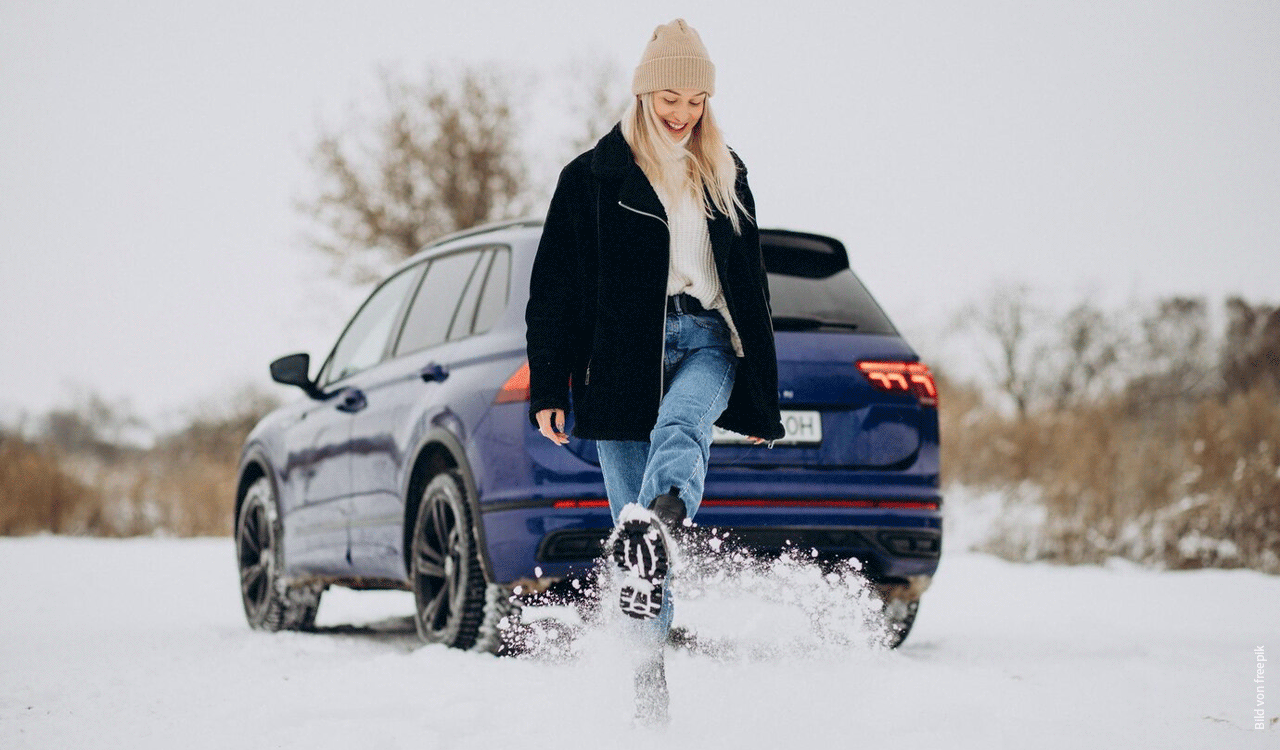 Junge Frau im Winter steht vor ihrem Auto